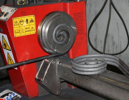 Cómo se fabrica un cabecero de forja, paso a paso en el taller 5 Voluta de hierro recién formada saliendo de la máquina curvadora
